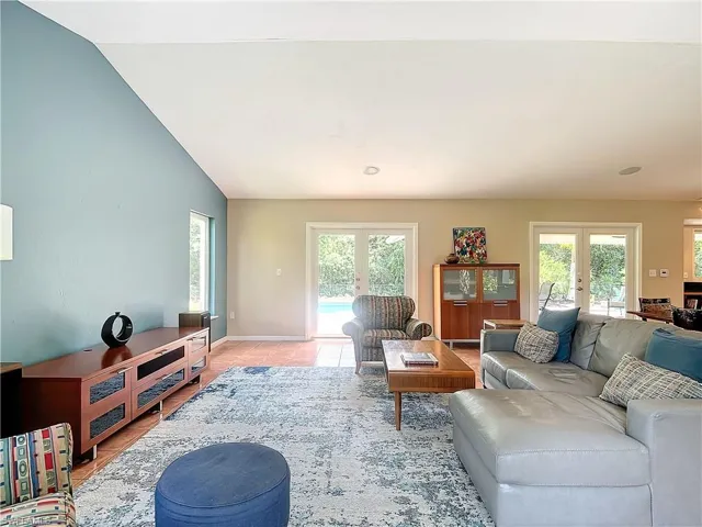 Living room featuring lofted ceiling and views of front, back and side yard. French doors leading to paver patio.