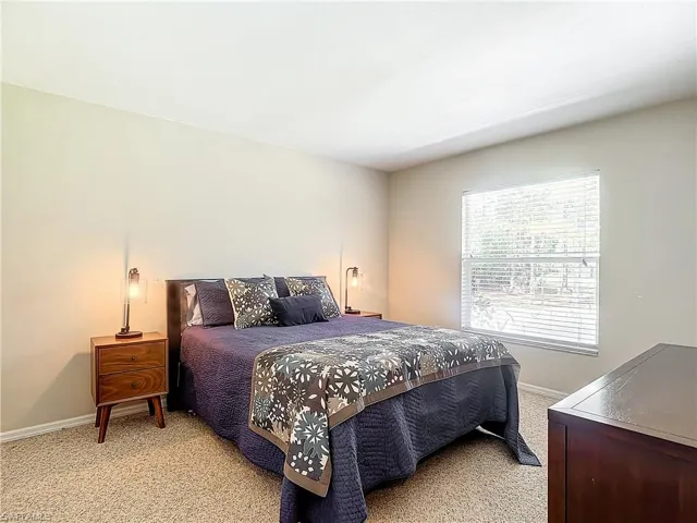 Nice sized guest bedroom with large window and light colored carpeting.