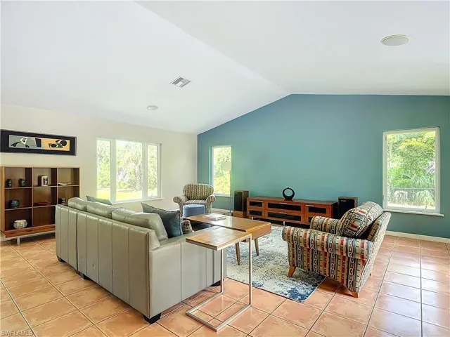 Tiled living room with natural light and vaulted ceiling.
