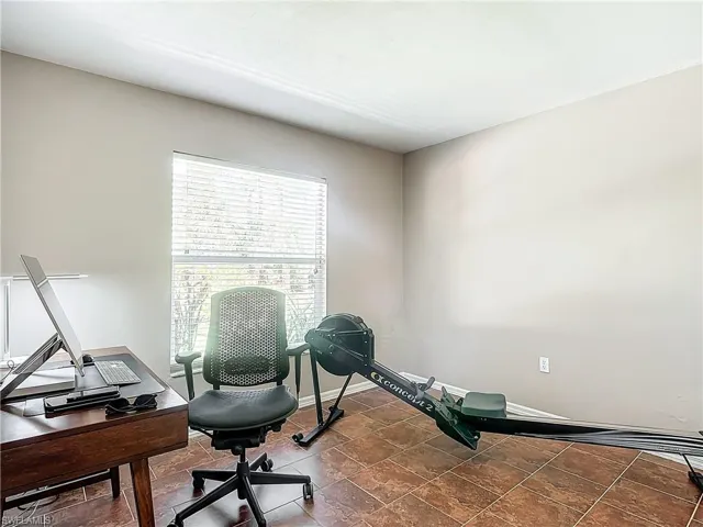 Guest bedroom with large window and closet, currently used as office/ workout space.