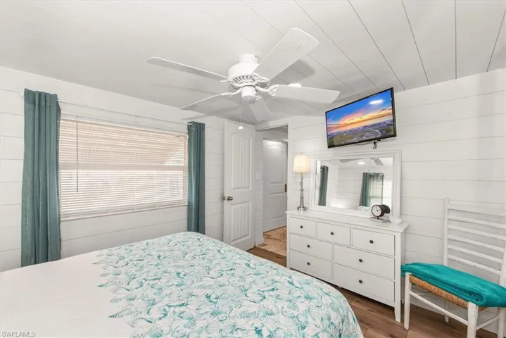 Bedroom with wood walls, wood finished floors, and ceiling fan