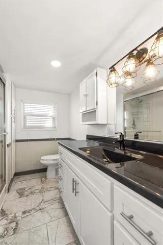 Bathroom with a stall shower, wainscoting, vanity, and light marble finish floors
