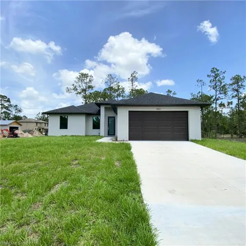 View of front of home with stucco siding, an attached garage, driveway, and a front yard