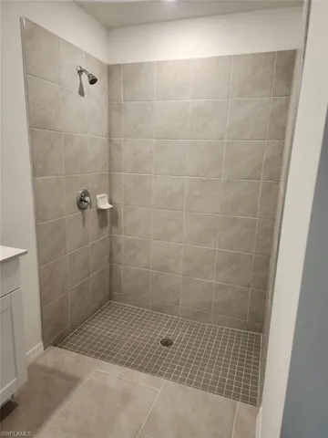 Full bathroom featuring vanity, a tile shower, and tile patterned floors
