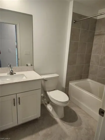 Bathroom with vanity, tub / shower combination, and light tile patterned floors