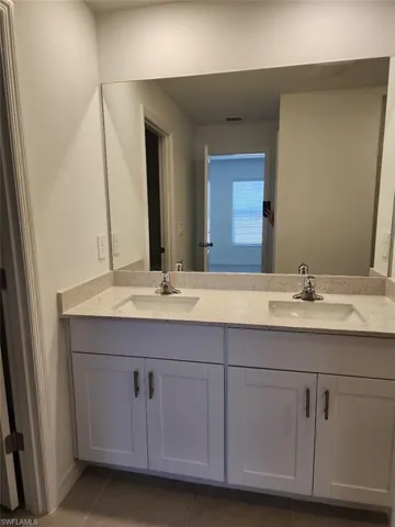 Bathroom with double vanity and dark tile patterned floors