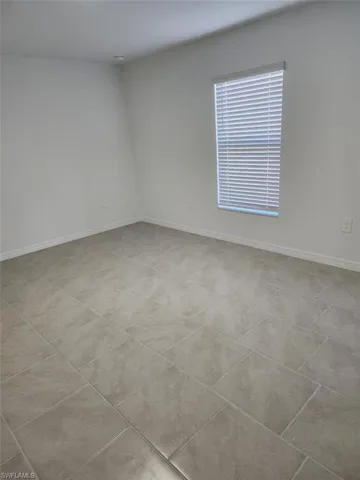 Empty room featuring baseboards and light tile patterned flooring