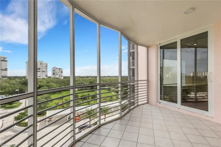 Curved balcony featuring tile flooring, a metal railing, and extensive glass paneling