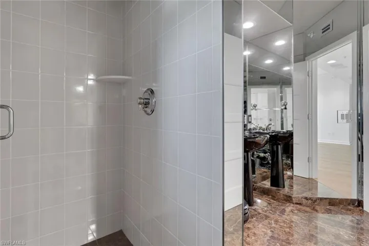 Shower with light-toned wall tiling and a built-in corner shelf