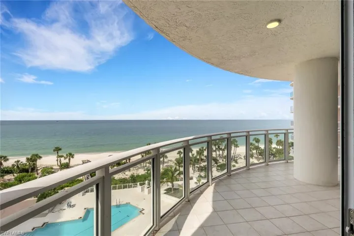 Curved balcony with tile flooring, glass railing, and overhead lighting