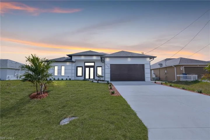 View of front facade with a garage and a lawn