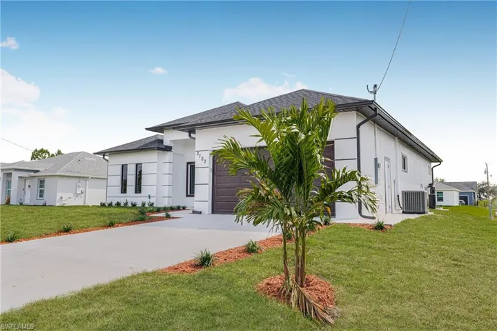 View of front facade featuring a garage, central AC, and a front yard