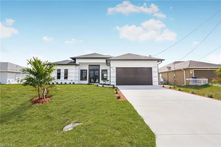 View of front of home with a garage and a front lawn