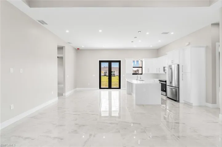 Kitchen featuring appliances with stainless steel finishes, sink, an island with sink, and white cabinets
