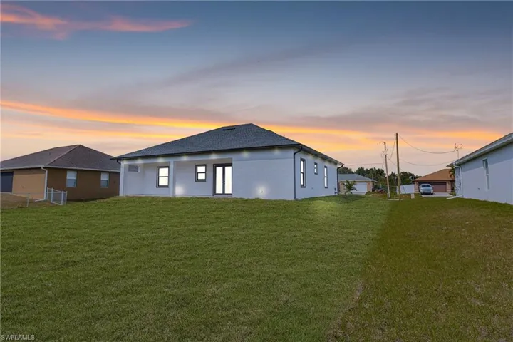 Back house at dusk with a yard