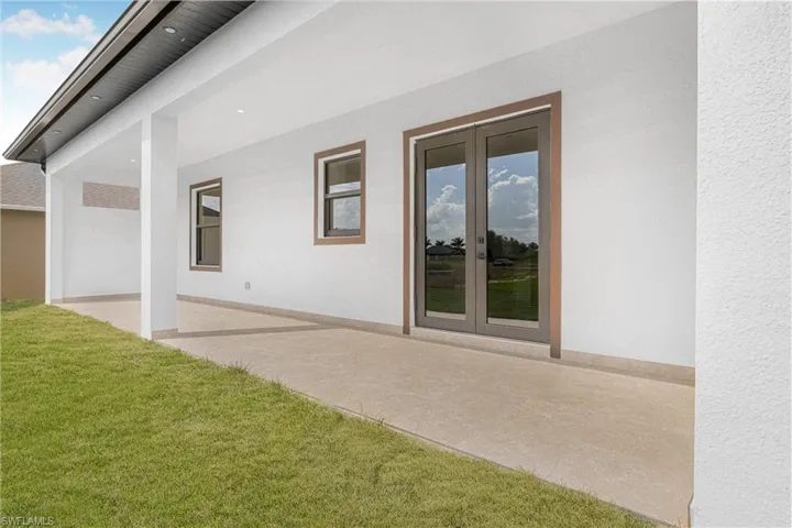 Rear view of property featuring french doors, a yard, and a patio