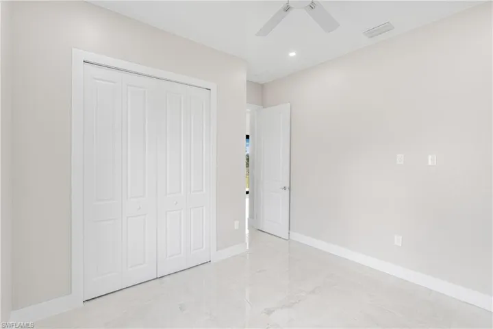 Unfurnished bedroom with ceiling fan and a closet