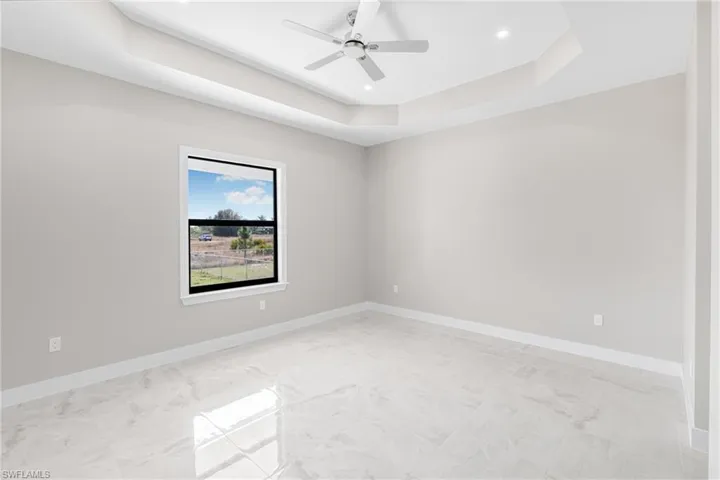 Unfurnished room featuring ceiling fan and a tray ceiling