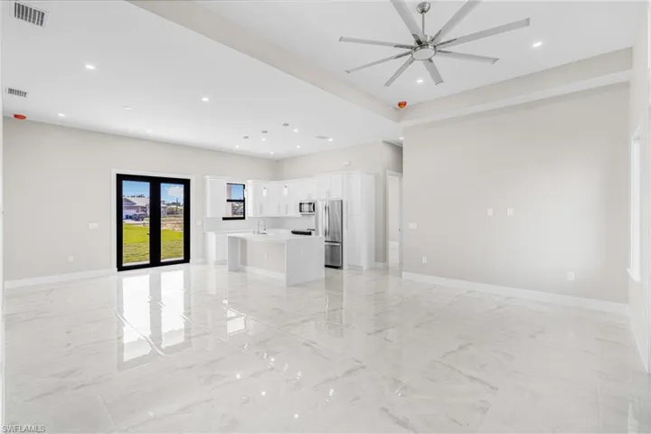 Unfurnished living room featuring sink, french doors, and ceiling fan