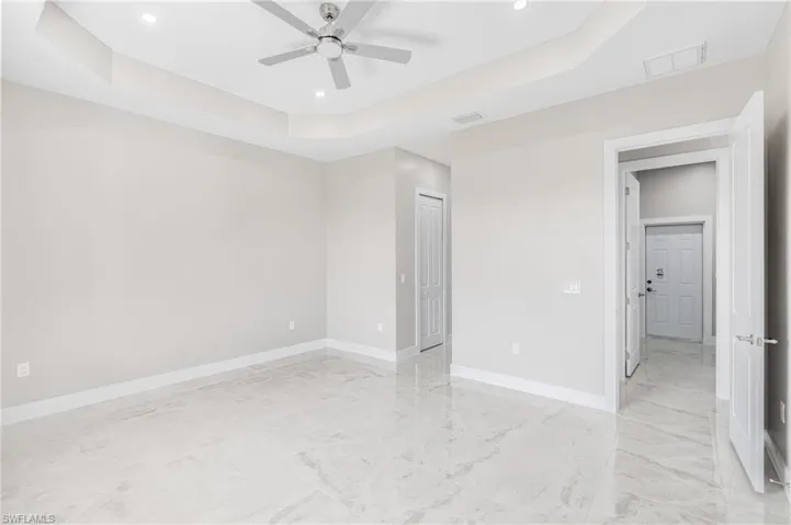 Unfurnished bedroom with a raised ceiling and ceiling fan