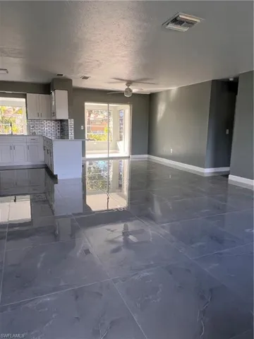 Unfurnished living room featuring ceiling fan, a healthy amount of sunlight, sink, and a textured ceiling