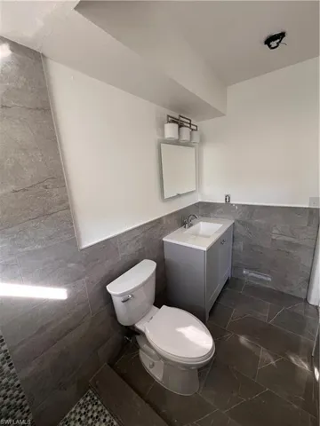 Bathroom featuring vanity, toilet, and tile walls