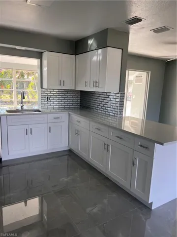 Kitchen with white cabinetry, sink, and kitchen peninsula