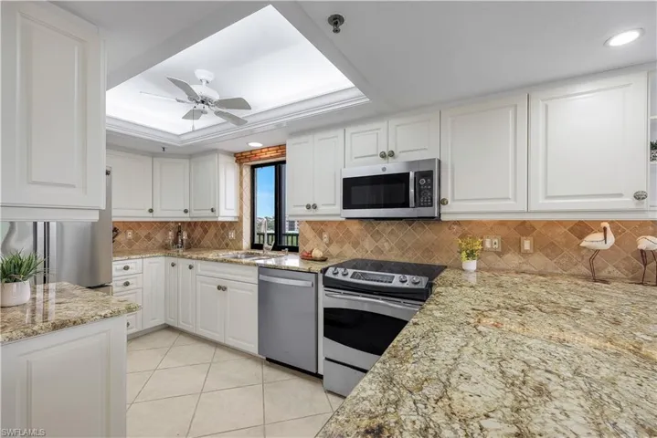 White cabinetry, granite-finish countertops, stainless steel appliances, tiled backsplash, and recessed lighting