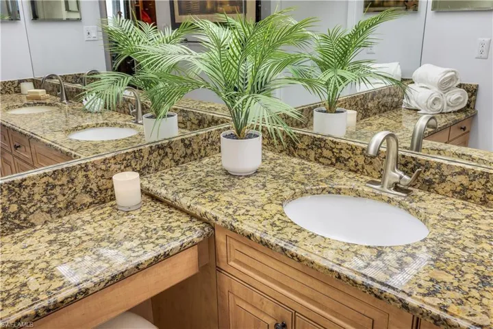 Double vanity with undermount sinks, stone countertops, light wood-finish cabinetry, and brushed nickel faucets