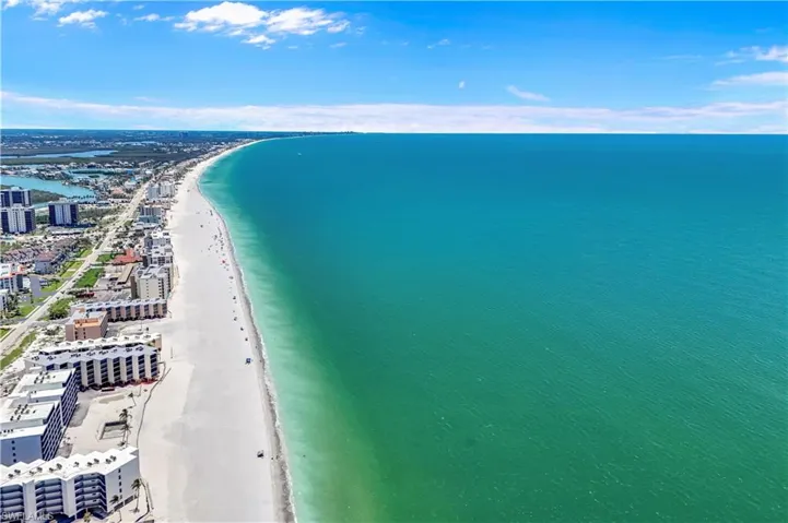 Expansive coastline with white sand beaches, clear blue waters, and surrounding urban development