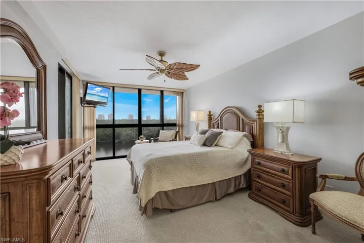 Wall-to-wall carpeting, expansive windows with vertical blinds, built-in ceiling fan, and light-toned walls