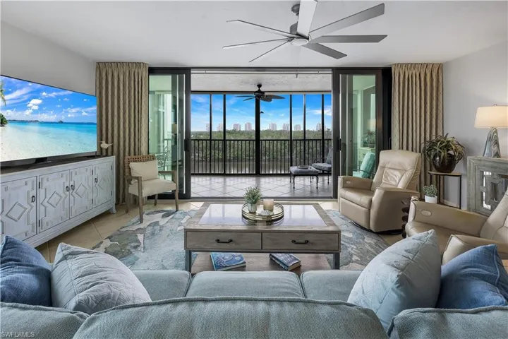 Sliding glass doors opening to an outdoor living area, tile flooring, ceiling fan, and built-in media console