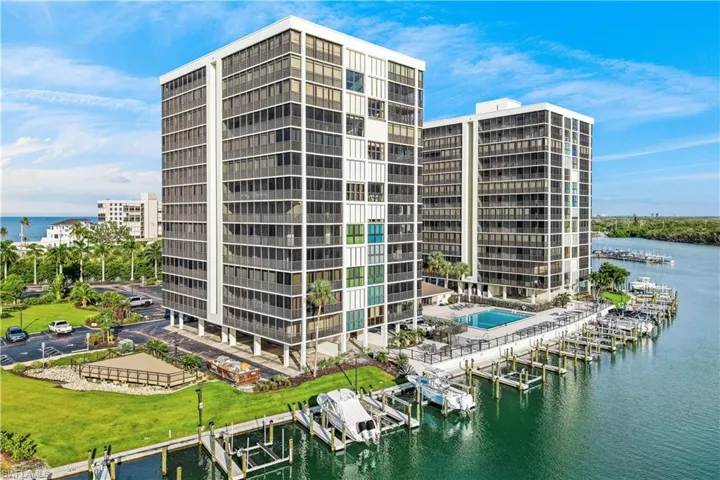 Waterfront high-rise building with multiple boat slips, a swimming pool, and manicured green spaces