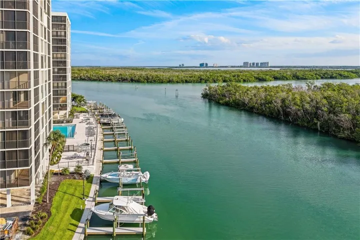 Waterfront property featuring multiple boat slips, a swimming pool with surrounding patio, and lush landscaping