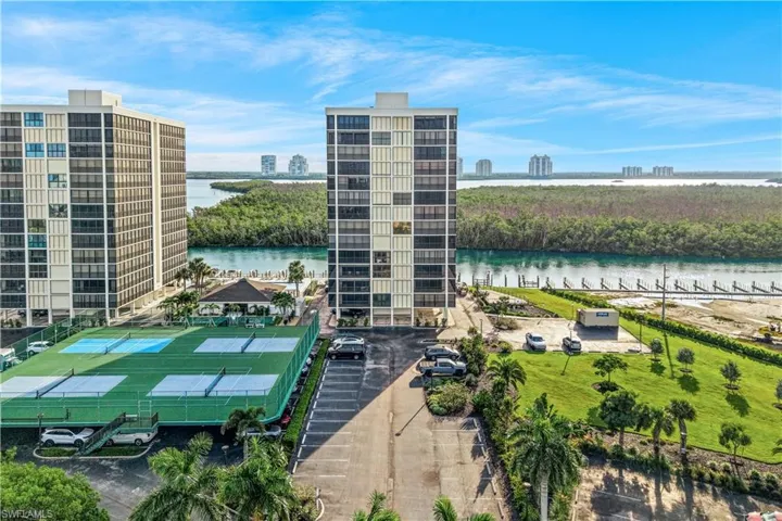 High-rise building with extensive waterfrontage, multi-court tennis facility, and surrounding green spaces