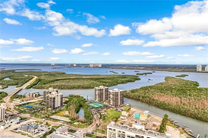 Waterfront residential community featuring multi-story apartment buildings with direct water access, mature landscaping, and expansive natural preserve surroundings