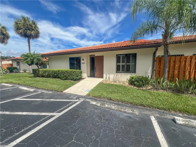 View of front of property with stucco siding, uncovered parking, and a tiled roof