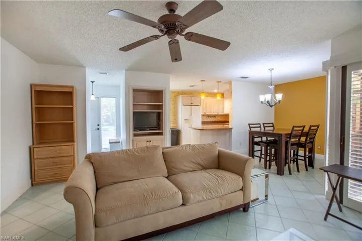 Living area with a textured ceiling, light tile patterned flooring, ceiling fan, and a chandelier