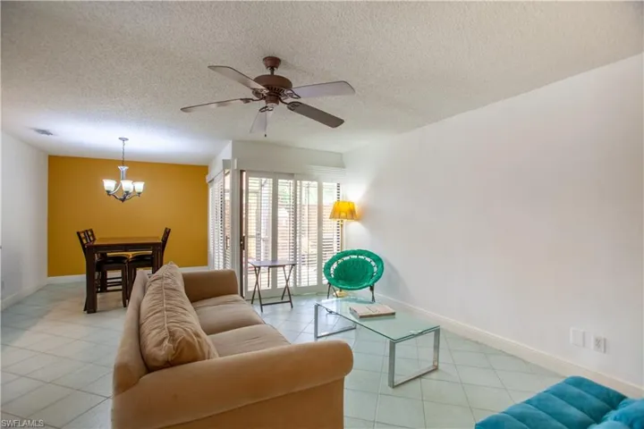 Living area featuring a textured ceiling, light tile patterned floors, ceiling fan, and a chandelier