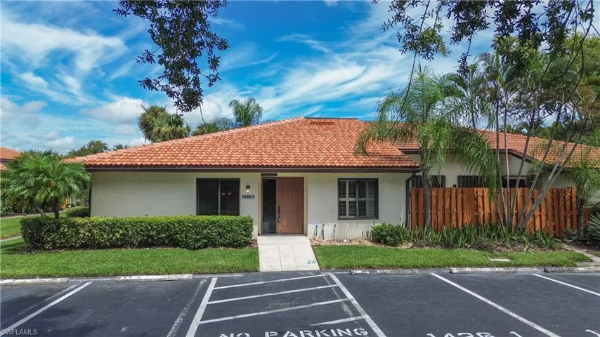 View of front of property featuring a tile roof, stucco siding, and uncovered parking