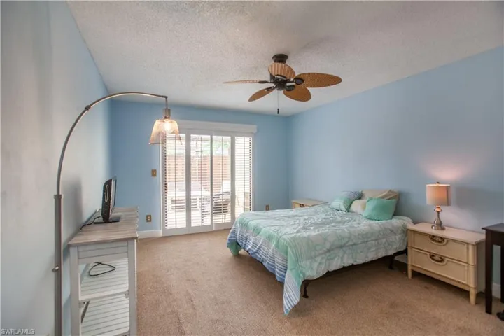 Carpeted bedroom featuring access to exterior, a textured ceiling, and a ceiling fan