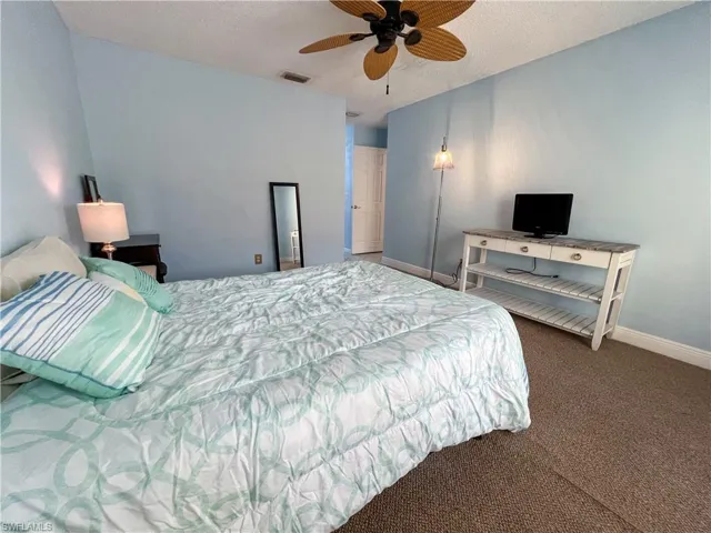 Carpeted bedroom featuring a textured ceiling and ceiling fan
