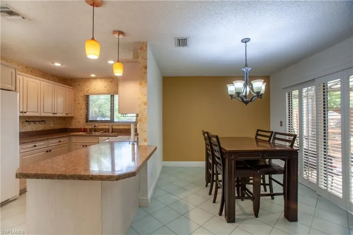 Dining room featuring a textured ceiling, light tile patterned flooring, a chandelier, and wallpapered walls