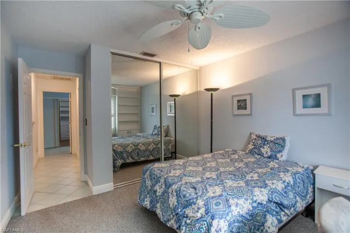 Carpeted bedroom featuring a textured ceiling, ceiling fan, tile patterned flooring, and a closet