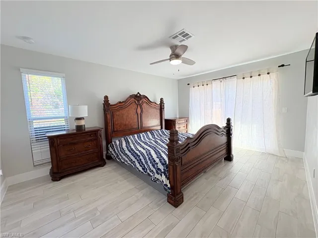 Bedroom with light wood-style floors, multiple windows, and ceiling fan