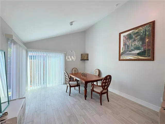 Dining area featuring wood tiled floors, plenty of natural light, a chandelier, and high vaulted ceiling