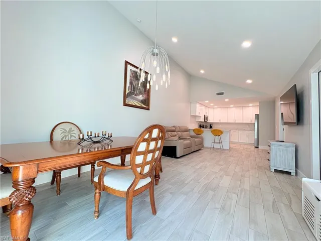 Dining space with wood tiled floors, recessed lighting, high vaulted ceiling, and a chandelier