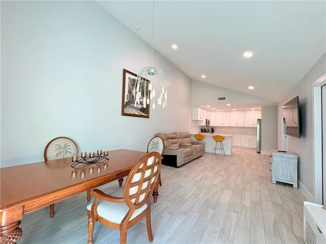 Dining room featuring vaulted ceiling, wood tiled floors, and recessed lighting