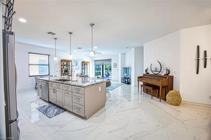 Kitchen with a center island with sink, light tile floors, gray cabinetry, sink, and appliances with stainless steel finishes