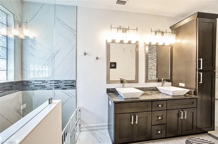 Bathroom featuring a tub, dual bowl vanity, and tile flooring